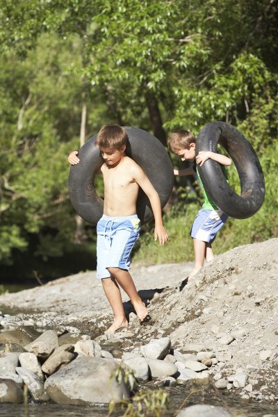 Two boys near the lake, holding big tyres to play with