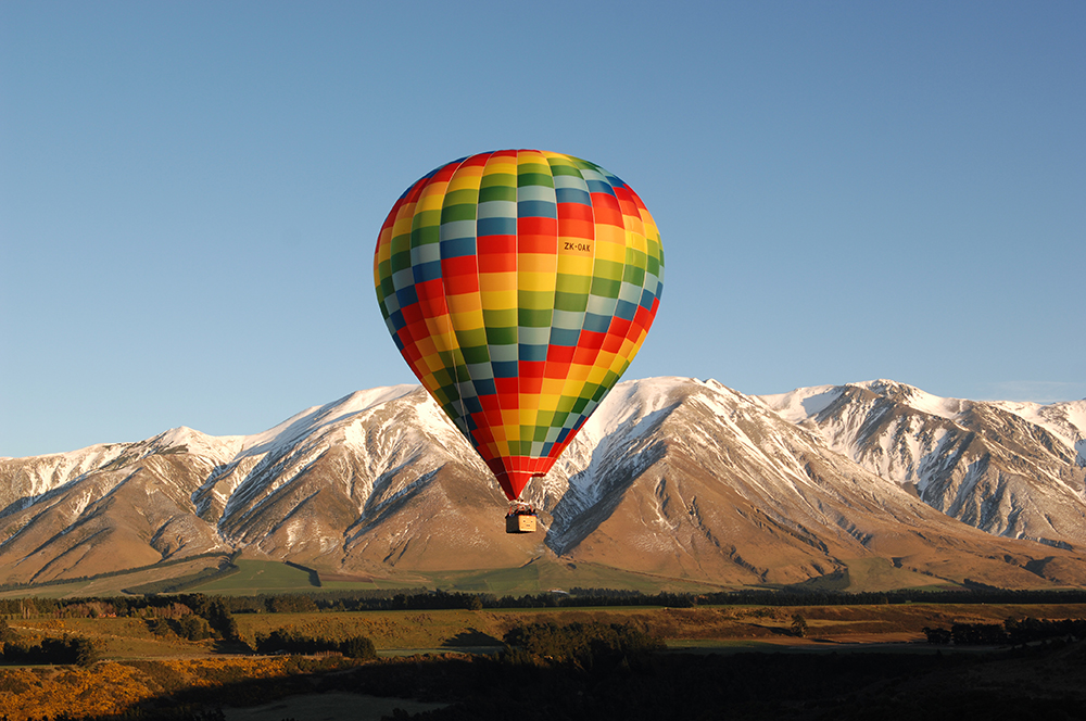 Hot air ballooning in Selwyn. colourful Balloon in the air, with a Mountain view