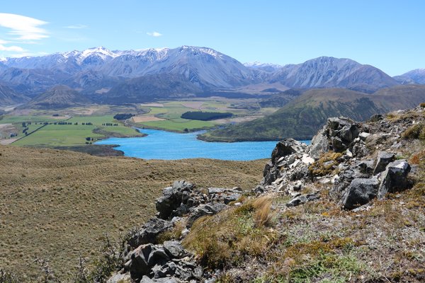 Beautiful blue lake in the middle of the fields, mountains in the background